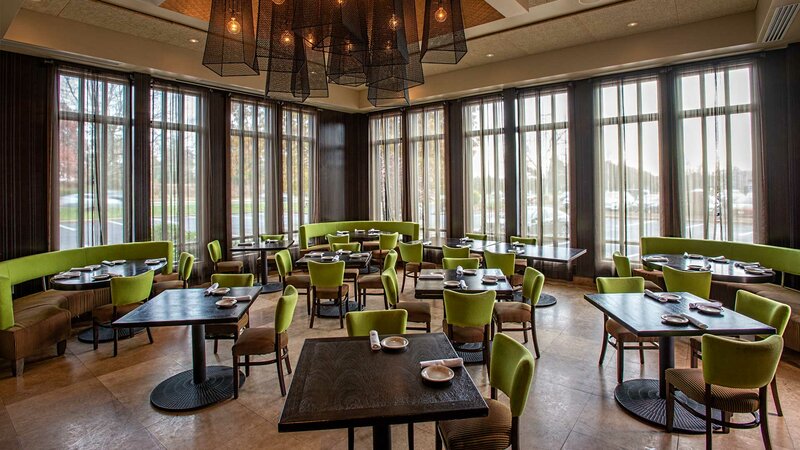 Dining room with many set tables with green chairs and view of the outside